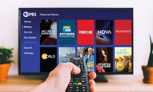 Hand holding remote control in front of TV screen displaying PBS Passport app