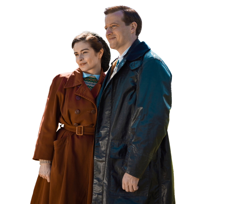 A woman in a brown coat and a man in a dark overcoat stand closely together, both looking off into the distance with calm expressions. The words "MASTERPIECE All Creatures Great and Small" are written to the right of the couple.